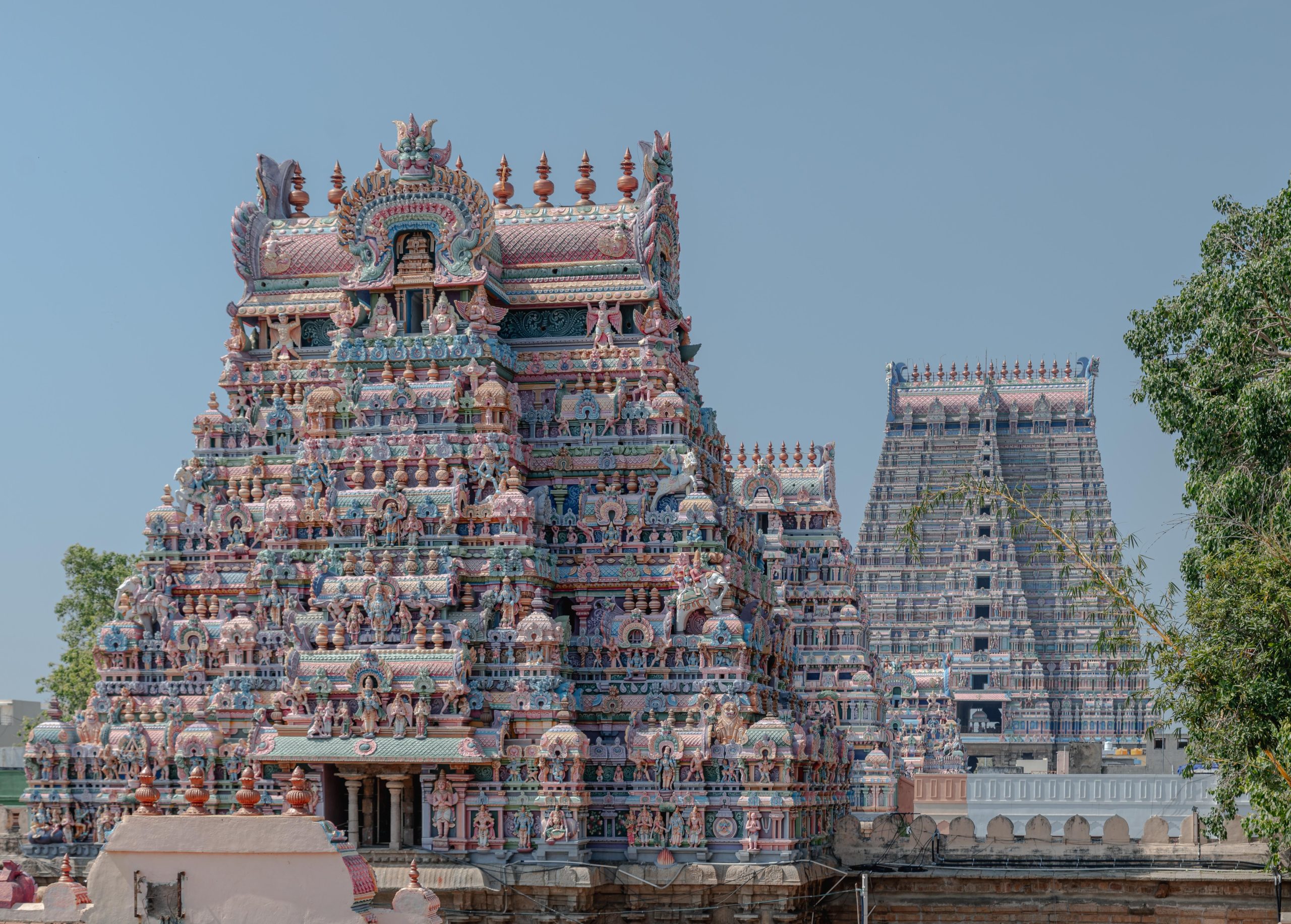 View of the colorful and detailed gopuram of the Srirangam Temple in Tiruchirappalli, India, under a clear blue sky.